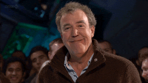Man In Brown Sweater Smiling At Crowd GIF