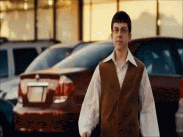 Man in Brown Vest in Front of Parked Cars