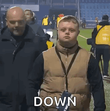 Man in Brown Vest Standing on Soccer Field