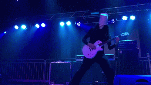 Man in Bucket Hat Playing Guitar on Stage