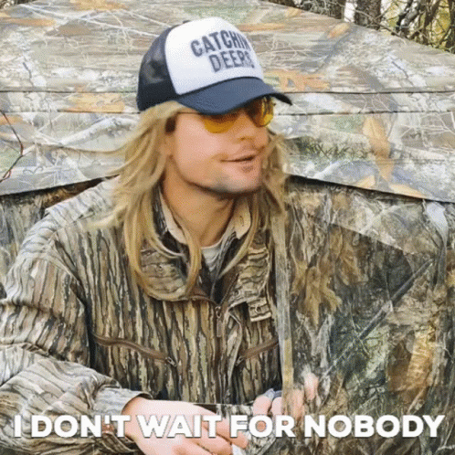 Man in Camouflage Tent Wearing Hat Saying Catchin Deer