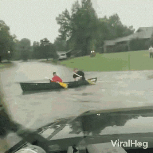 Man In Canoe Pulled By Car In Flooded Street GIF