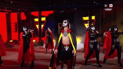 Man in Cape Surrounded by Women in Black and Red