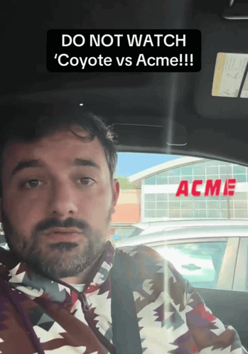 Man in Car With Acme Sign