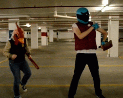Man in Chicken Mask Next to Man in Blue Helmet