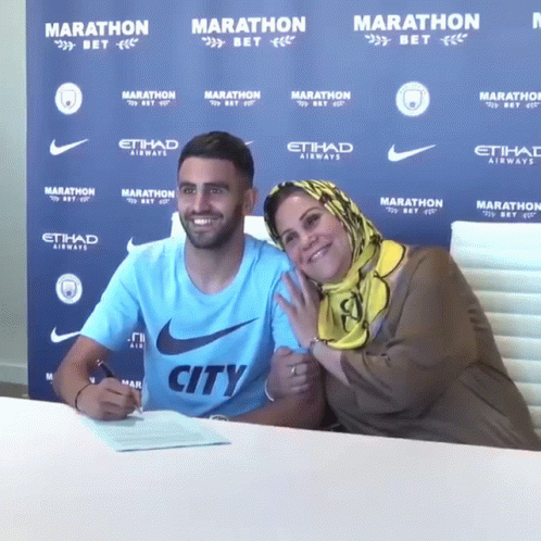 Man in City Shirt Signing Document with Mother