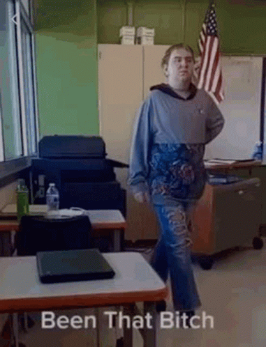Man in Classroom With Laptop and Flag