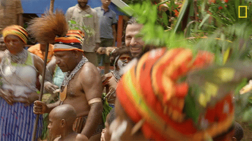 Man In Colorful Hat In Crowd With National Geographic Logo GIF
