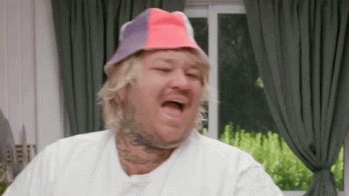 Man In Colorful Hat Making Funny Face In Living Room GIF