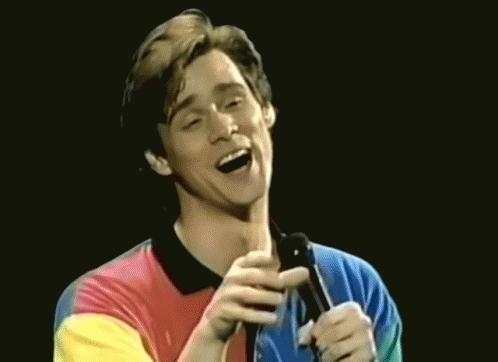 Man in Colorful Shirt Singing Into Microphone and Laughing