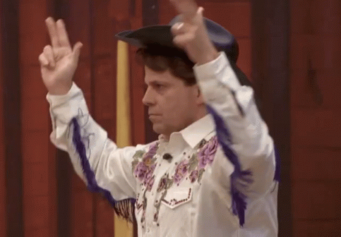 Man in Cowboy Hat and Purple Fringe Giving Peace Sign