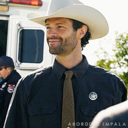 Man in Cowboy Hat and Tie in Front of Police Vehicle
