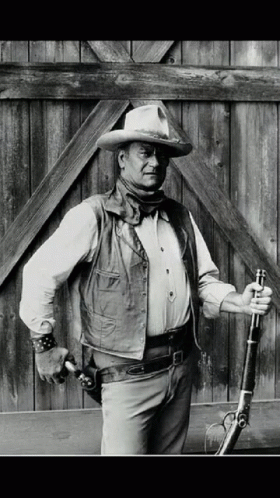 Man in Cowboy Hat and Vest Holds Gun