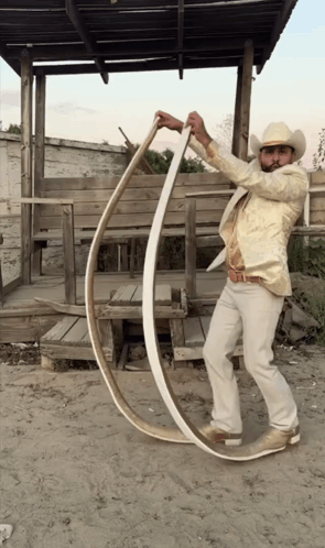 Man in Cowboy Hat Holding Long Wood