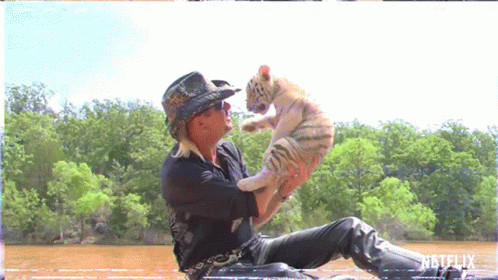 Man in Cowboy Hat Holding Small White Tiger