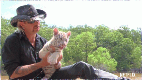 Man in Cowboy Hat Holding Small White Tiger