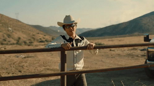 Man in Cowboy Hat Leaning on Fence
