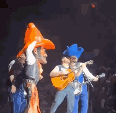 Man in Cowboy Hat Playing Guitar on Stage