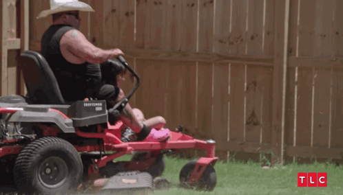 Man in Cowboy Hat Riding Lawn Mower with Daughter