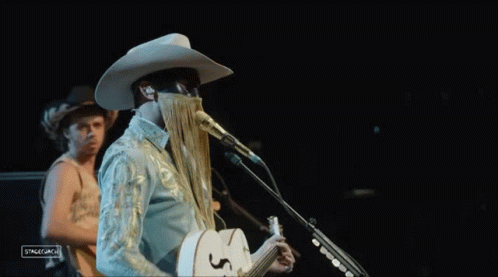Man in Cowboy Hat Singing Into Microphone