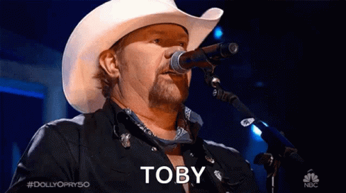 Man in Cowboy Hat Singing Into Microphone With Word Toby