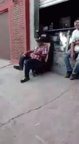 Man in Cowboy Hat Sitting on Sidewalk Chair