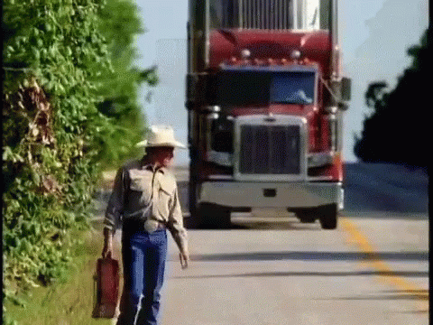 Man in Cowboy Hat Walking in Front of Red Semi Truck
