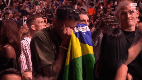 Man In Crowd Covering Face With Brazilian Flag GIF