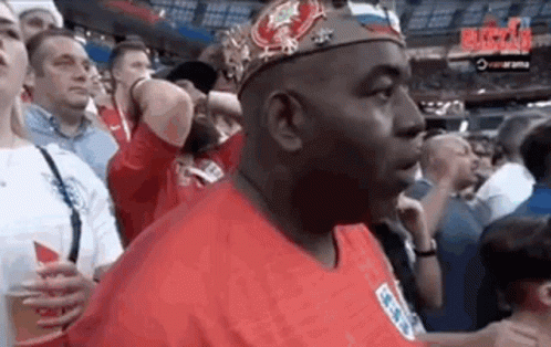 Man in Crown and Red Shirt Standing in Crowd
