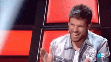 Man in Denim Jacket Laughing by Red Couch