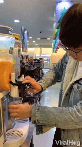 Man in Denim Jacket Pouring Orange Juice at Vending Machine