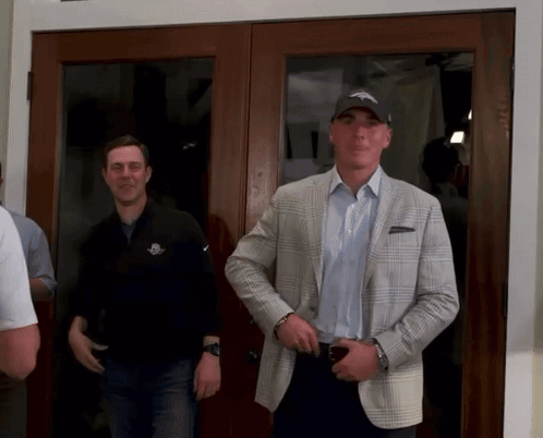Man in Denver Broncos Hat in Front of Glass Door