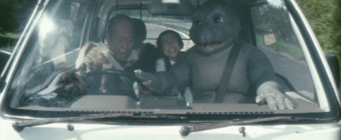 Man in Dinosaur Costume Driving Car With Two Kids