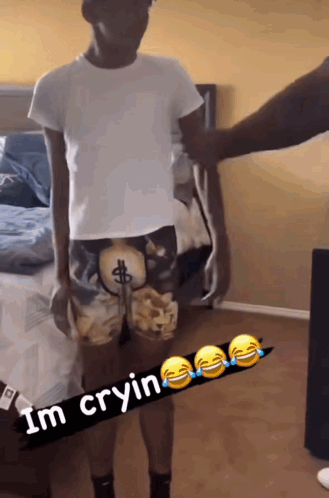 Man in Dollar Sign Shorts Beside Bed