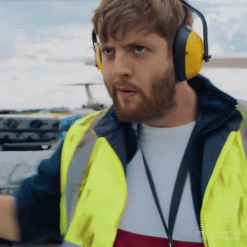 Man in Ear Muffs Yellow Vest Near Airplane