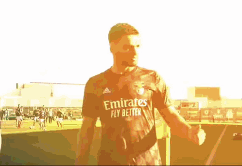 Man in Emirates Fly Better Shirt Standing on Field