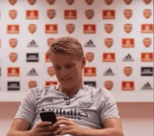 Man In Emirates Shirt Looking At Cell Phone GIF