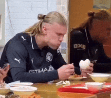 Man in Etihad Shirt at Table With Bowls of Food