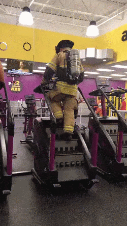 Man in Fireman Uniform Riding Treadmill at Gym
