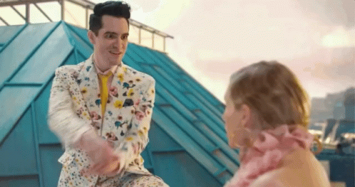 Man in Floral Suit Shaking Hands with Woman in Pink