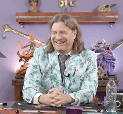 Man in Floral Suit Smiling With Folded Hands at Desk