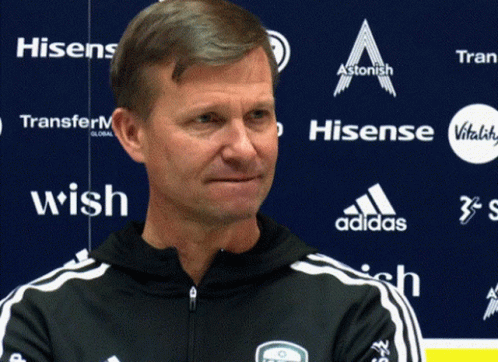 Man In Front Of Blue Wall With Hisense And Adidas Logos GIF
