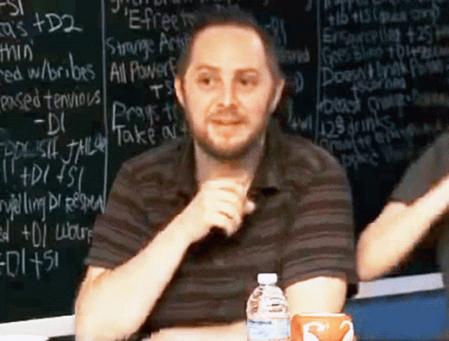Man in Front of Chalkboard Saying Strange Artifact