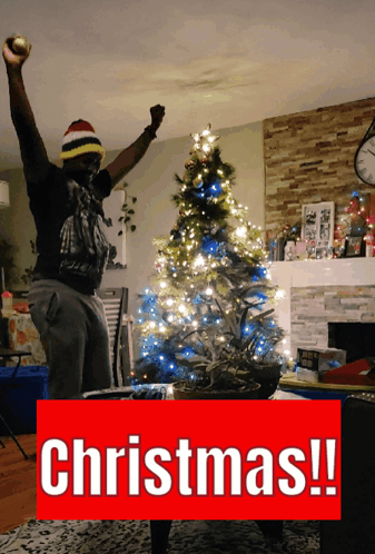 Man in Front of Christmas Tree With Word Christmas Below