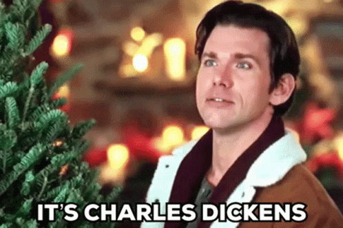Man in Front of Christmas Tree With Words It's Charles Dickens