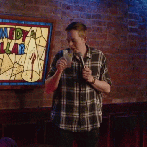 Man in Front of Comedy Sign