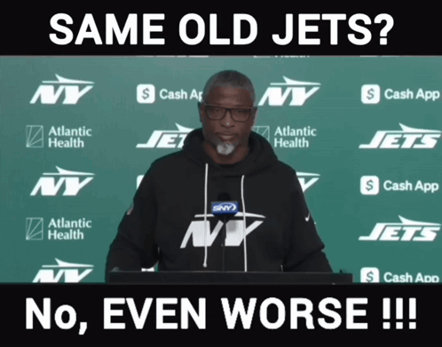 Man In Front Of Green Backdrop With NY Jets Logos GIF