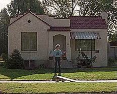 Man in Front of Small House with Red Roof