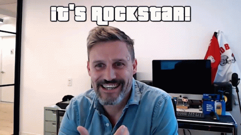 Man in Front of Wall Saying It's Rockstar