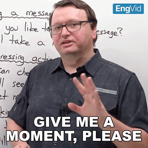 Man in Front of White Board Saying Give Me a Moment Please